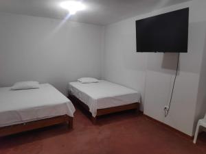 a room with two beds and a flat screen tv at Amenli Lodging House in Piura