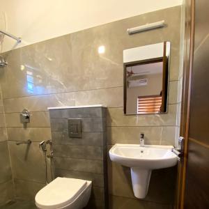 La salle de bains est pourvue d'un lavabo, de toilettes et d'un miroir. dans l'établissement Nimet Residency, à Ernakulam
