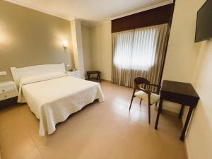 1 dormitorio con cama, escritorio y ventana en Hotel O Cruceiro, en Caldas de Reis