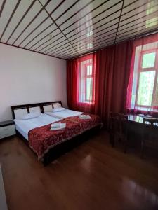a bedroom with a bed with red curtains at Pekin Hotel in Temirtaū