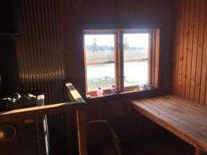 a room with a window with a bench and a table at Cozy lodge at horse farm with lake and sauna in Hölö