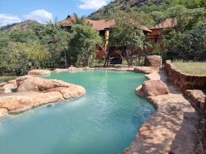 a pool of water with rocks in front of a house at Waterfall Safari Lodge in Winterkamp