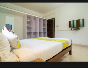 1 dormitorio con 1 cama grande y TV en la pared en Tharayil Apartments en Kochi