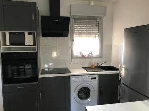 a kitchen with a washing machine and a microwave at appartement T3 in Aureilhan