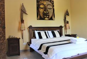 a bedroom with a bed with a painting on the wall at Silvy Guesthouse in Canggu
