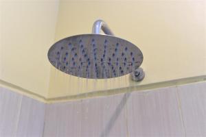 a metal shower head on a wall in a bathroom at Silvy Guesthouse in Canggu