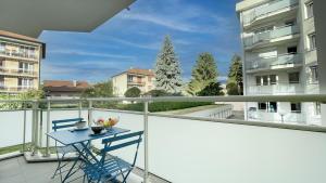 a blue table on a balcony with a view of a building at HOMEY WOOD - New - Appartement avec une chambre - Parking privé gratuit - Balcon privé - A 5 min de la gare pour rejoindre Genève in Annemasse