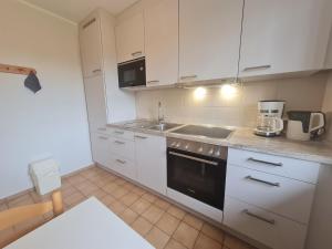 uma cozinha com armários brancos e um forno com placa de fogão em "Pappelhof - Whg 3" em Grömitz