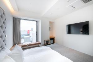 ein Hotelzimmer mit einem Bett und einem TV in der Unterkunft THE KNOT SAPPORO in Sapporo