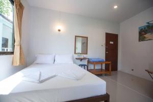 a bedroom with a white bed and a mirror at Kamala bay inn in Kamala Beach