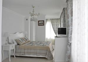 a white bedroom with a bed and a television at Lara Ilica Hotel in Cesme