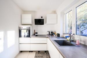 een keuken met witte kasten, een wastafel en een raam bij Komfort Deluxe in Ludwigshafen am Rhein