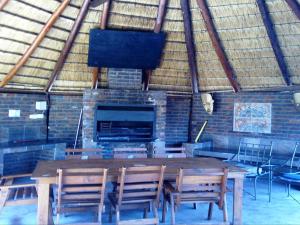 Hornbill Private Lodge Mabalingwe في Mabula: غرفة مع طاولة وكراسي خشبية ومدفأة