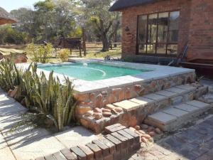 Hornbill Private Lodge Mabalingwe في Mabula: حمام سباحة في ساحة مع منزل من الطوب