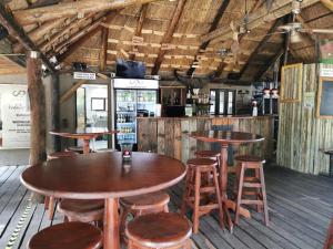un restaurante con mesas de madera y taburetes en una habitación en Hornbill Private Lodge Mabalingwe, en Mabula