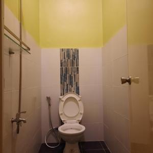 a bathroom with a toilet with a yellow ceiling at bluenest apartment in Manila