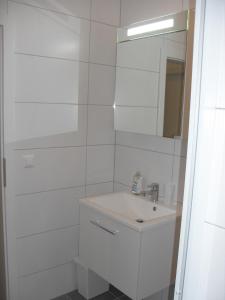 ein weißes Badezimmer mit einem Waschbecken und einem Spiegel in der Unterkunft Ferienwohnung Rockside in Arnoldstein