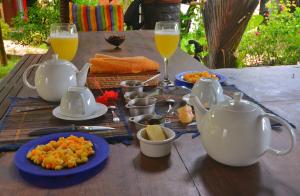 stół z talerzami jedzenia i szklanki soku pomarańczowego w obiekcie Hotel Benjamin w mieście Ambatoloaka