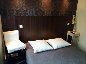 Cette chambre comprend un lit avec deux oreillers et une chaise. dans l'établissement Hotel Les Negociants, à Valence