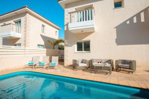 een zwembad met stoelen en een tafel en een huis bij Protaras Holiday Villa 035 in Protaras