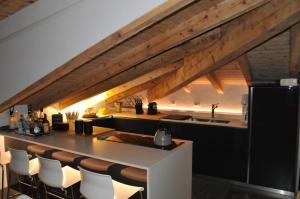 a kitchen with a counter and a bar with chairs at Mansarda la Baita in Madonna di Campiglio