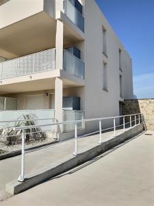 un edificio blanco con una pasarela delante de él en Studio à 600m de la mer dans une résidence récente, en Sérignan