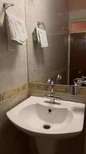 ナガルコットにあるHotel Valley View Innのバスルーム(白い洗面台、鏡付)