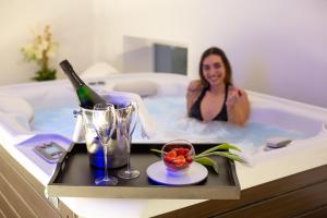 una donna seduta in una vasca da bagno con una bottiglia di vino di Hotel Lago Di Garda a Torbole