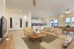 a living room with couches and a table and a kitchen at Villa Haka Jimbaran by Nagisa Bali in Jimbaran