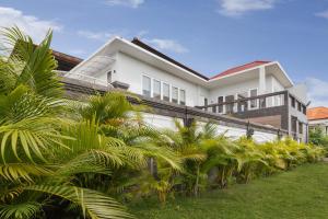 a white house with palm trees in front of it at Villa Haka Jimbaran by Nagisa Bali in Jimbaran