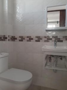 a white bathroom with a toilet and a sink at Lux suites Utawala Family House in Nairobi