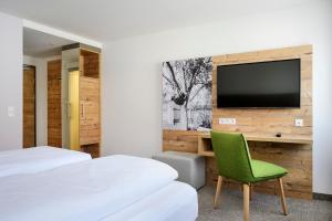 a bedroom with a television and a green chair at ApartHotel Rose in Ellwangen