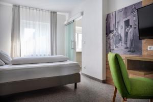 a bedroom with a bed and a green chair at ApartHotel Rose in Ellwangen