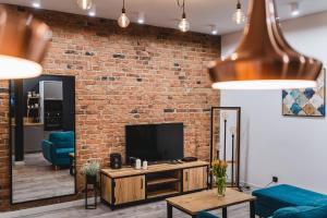 a living room with a brick wall and a tv at Modern Apartments Toruń 2 in Toruń