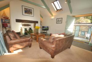 a living room with two leather couches and a fireplace at Granary at Trewerry Cottages - Away from it all, close to everywhere in Newquay