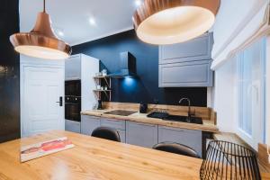 Una cocina con paredes azules y una mesa de madera. en Modern Apartments Toruń 2 Stare Miasto-Centrum, en Toruń