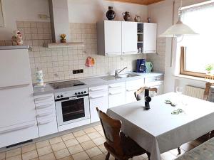 eine weiße Küche mit einem Tisch und einem Waschbecken in der Unterkunft Apartment in Eifel near Nürburgring in Oberstadtfeld