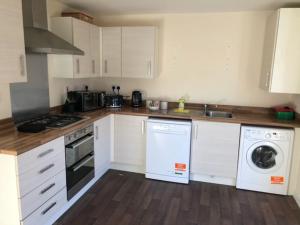 a kitchen with white cabinets and a washer and dryer at Bray House - Perfect for Large Groups in Wolverhampton