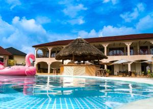 una piscina con sombrilla de paja y una balsa inflable rosa en Paje Blu Boutique Hotel, en Paje