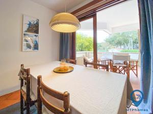 ein Esszimmer mit einem weißen Tisch mit Stühlen und einem großen Fenster in der Unterkunft Balaia Beach T2 com piscina in Albufeira