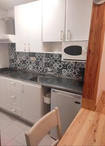 eine Küche mit weißen Schränken, einer Spüle und einer Mikrowelle in der Unterkunft Apartamento bonito Molina Alp in La Molina