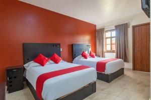 2 camas en una habitación de hotel con paredes rojas en OYO Hotel Emperadores Inn, Atlixco en Atlixco