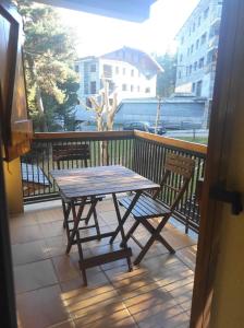 d'une table en bois et de deux chaises sur un balcon. dans l'établissement Apartamento bonito Molina Alp, à La Molina