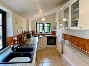 a kitchen with a sink and a counter top at Jubilee Cottage in Sidbury