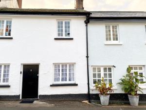 a white house with a black door and windows at Cloud Nine in Otterton