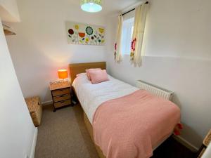um pequeno quarto com uma cama com um cobertor rosa em Cloud Nine em Otterton