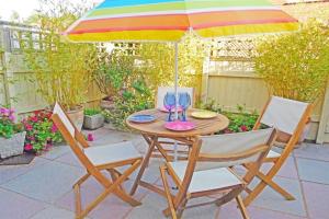 einen Holztisch mit zwei Stühlen und einem Sonnenschirm in der Unterkunft Bethany Cottage in Sidmouth