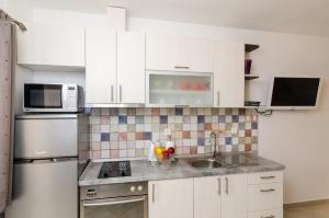 a kitchen with white cabinets and a sink and a microwave at Apartments Aurelia in Dubrovnik