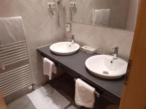 Baño con 2 lavabos en una encimera negra en Land-gut-Hotel Zum alten Forsthaus - Aufladestation für Elektroautos, en Hürtgenwald