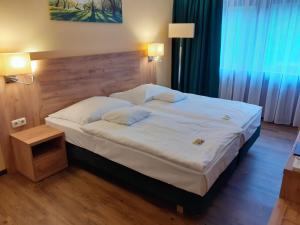 a bedroom with a large white bed with a wooden headboard at Land-gut-Hotel Zum alten Forsthaus - Aufladestation für Elektroautos in Hürtgenwald